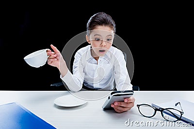 Little girl businesswoman holding cup and using smartphone Stock Photo