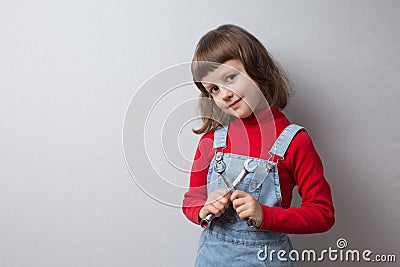 A little girl in a car mechanic uniform is holding wrenches Stock Photo