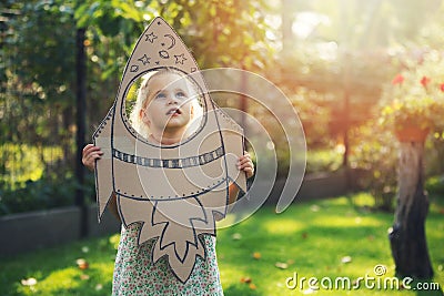 Little girl with cardboard rocket dreaming about flying in space and astronaut profession in future. imagination, freedom and Stock Photo