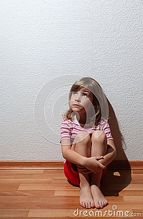 Little girl in casual clothes looks sad to corner Stock Photo