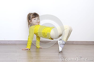 Little girl in casual yellow clothes doing gymnastics at home Stock Photo
