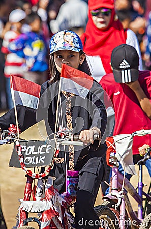 A little girl celebrate Indonesian Independence day, bring Indonesian flag the red and white flag in the bicycle Editorial Stock Photo