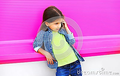 Little girl child calling on smartphone on city street on colorful pink wall Stock Photo