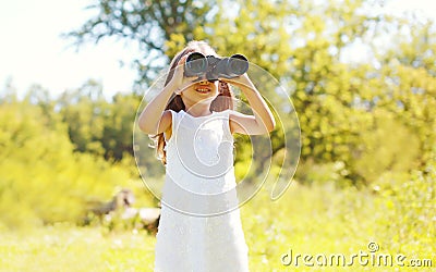 Little girl child looks in binoculars outdoors in summer Stock Photo