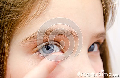 Little girl child putting contact lens into her eye closeup Stock Photo