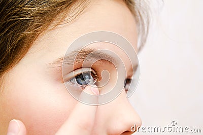 Little girl child putting contact lens into her eye closeup Stock Photo