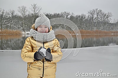 Little girl child in winter sculpts a snowman from the snow. Stock Photo