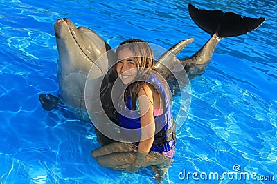 Little girl children hugging a gorgeous dolphin flipper smiling face happy kid swim bottle nose dolphins Stock Photo