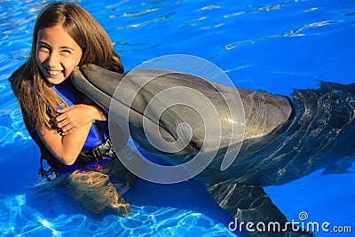 Little girl children kissing a gorgeous dolphin flipper smiling face happy kid swim bottle nose dolphins Stock Photo