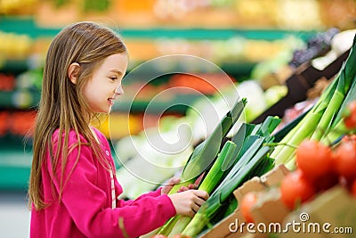 Little girl choosing fresh leek in a food store Stock Photo