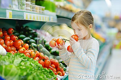 Little girl choosing tomatoes in a food store Stock Photo