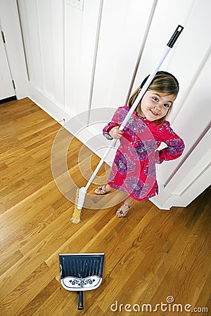 Little girl cleaning with broom looking up Stock Photo