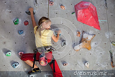 Little girl climbing a rock wall indoor. Stock Photo