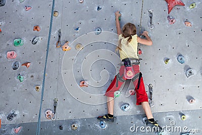 Little girl climbing a rock wall indoor. Stock Photo