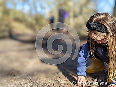 A little girl collects stones from the pathway Stock Photo