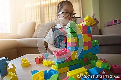 Little girl in a colorful shirt playing with construction toy blocks building a tower Stock Photo