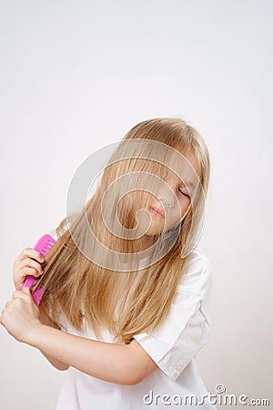 little girl combs long and tangled hair. white background. Stock Photo