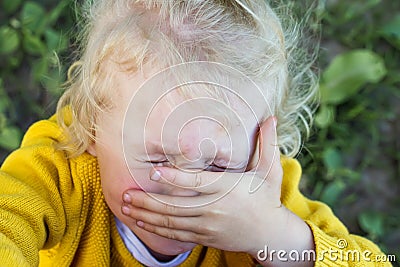 little girl cries, covering face with hands. injured child runs to mother for help. Close up portrait of crying little Stock Photo