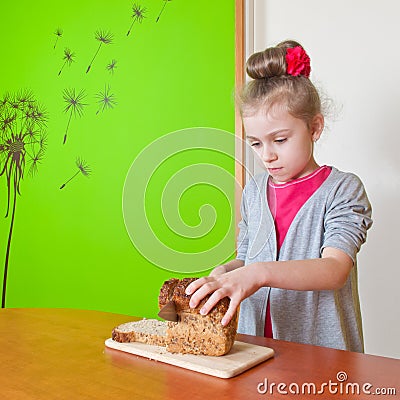 Little girl cuts the bread Stock Photo