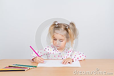 Little girl draws at table pencils. Stock Photo
