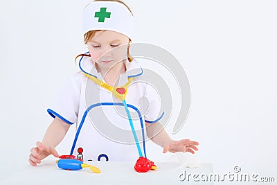 Little girl dressed as nurse plays with toy medical instruments Stock Photo