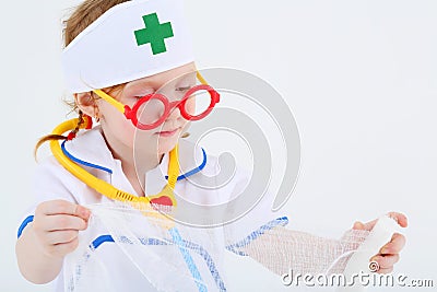 Little girl dressed as nurse spreads bandage Stock Photo