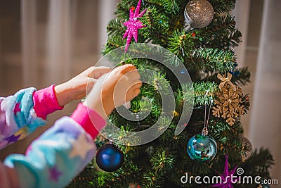 Little girl dressed up as a reindeer Rudolf decorating a Christmas tree Stock Photo