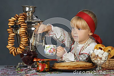 Little girl drinking tea in the traditional russian sarafan and shirt Stock Photo