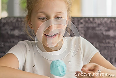 Little girl eating blue ice cream in a cafe. Girl delighted with ice cream. Adorable little girl eating ice cream at summer. close Stock Photo