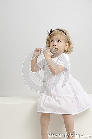 Little girl eating a chocolate lollypop Stock Photo