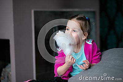 Little girl eat sweet cotton candy at home. Happy kindergartener bite candy floss. Favourite sweets, sugary food. Stock Photo