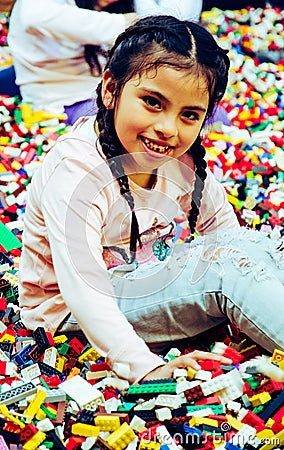 Little girl with educational toy blocks. Children play at day care or preschool. Mess in kids room. Stock Photo