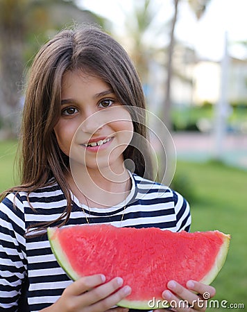 Little girl in an elegant dress and hat eats a watermelon Stock Photo