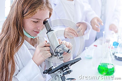 Little girl at an elementary school, using microscope research, testing in science class. Toddler girl doing biochemistry research Stock Photo