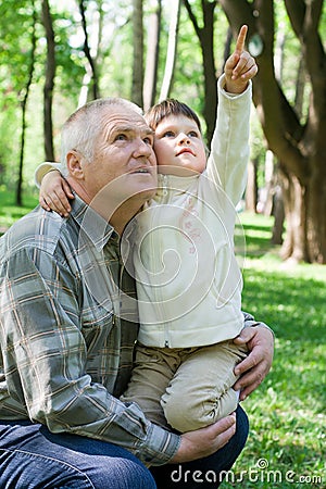 Little girl embraces grandfather, sits on arms and Stock Photo