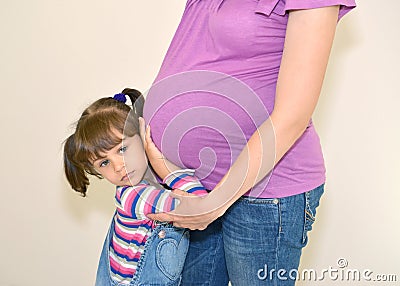 The little girl embraces hands a stomach of pregnant mother Stock Photo