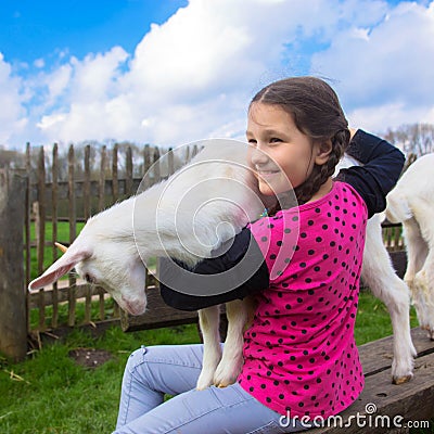 Little girl embracing a kid goat on a farm. Stock Photo