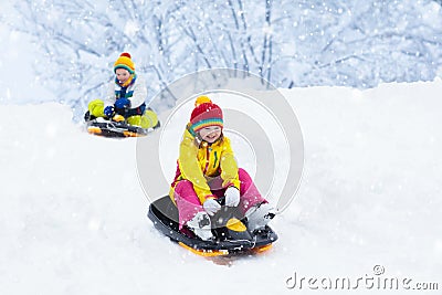 Little girl enjoying a sleigh ride. Child sledding. Toddler kid riding a sledge. Children play outdoors in snow. Kids sled in the Stock Photo