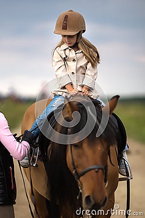 Little girl in equestrian helmet riding a horse Stock Photo