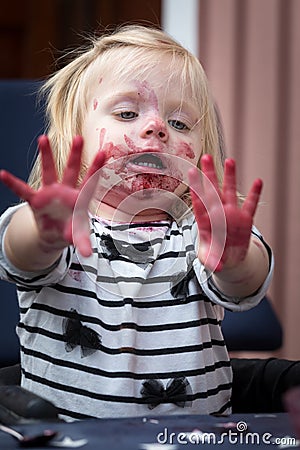 A surprised facial appearance when a sweet little girl examines her fingers after a blueberry fiesta. Stock Photo