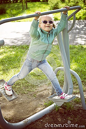 Little girl exercising on outdoor fitness machine Stock Photo