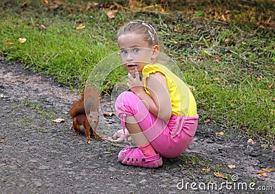 Little girl feeding squirrel with nuts Stock Photo