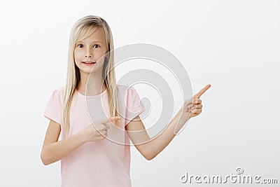 Little girl feeling intense pointing at friend who did mess in classroom during break. Awkward adorable child with blond Stock Photo