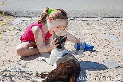 Little girl holding head of a cat sitting on the ground Stock Photo