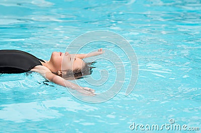 Little girl floating in swimming pool Stock Photo