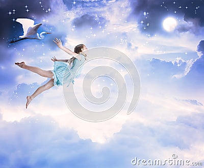 Little girl flying into the blue night sky Stock Photo