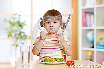 Little girl with fork and knife ready to eat Stock Photo