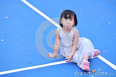 The little girl is funny face while sitting on the tennis court. Stock Photo