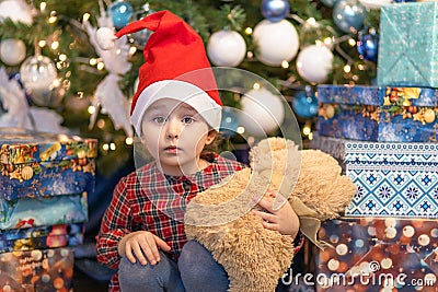 Little girl with gift under christmas tree. surprised child with teddy bear for new year. kid and soft toy on xmas Stock Photo