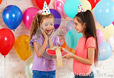 Little girl giving her friend birthday gift at party Stock Photo